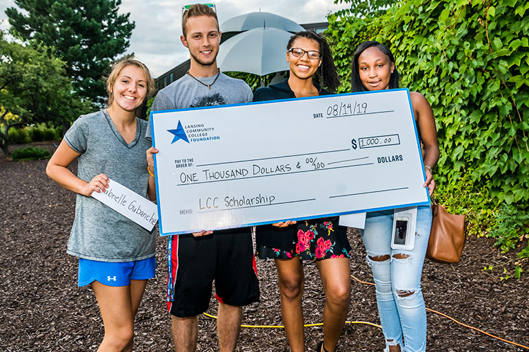 four students holding a large scholarship check