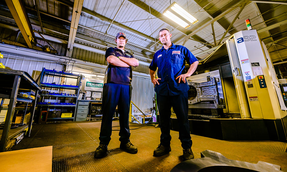 two apprenticeship students looking at the camera at a downward  angle with their arms crossed