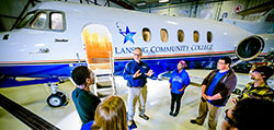Teacher instructs group of students in front an LCC jet inside the hanger at the Mason Jewett Airport