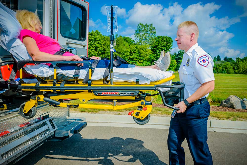 EMS Technician wheeling women on a stretcher up into an ambulance