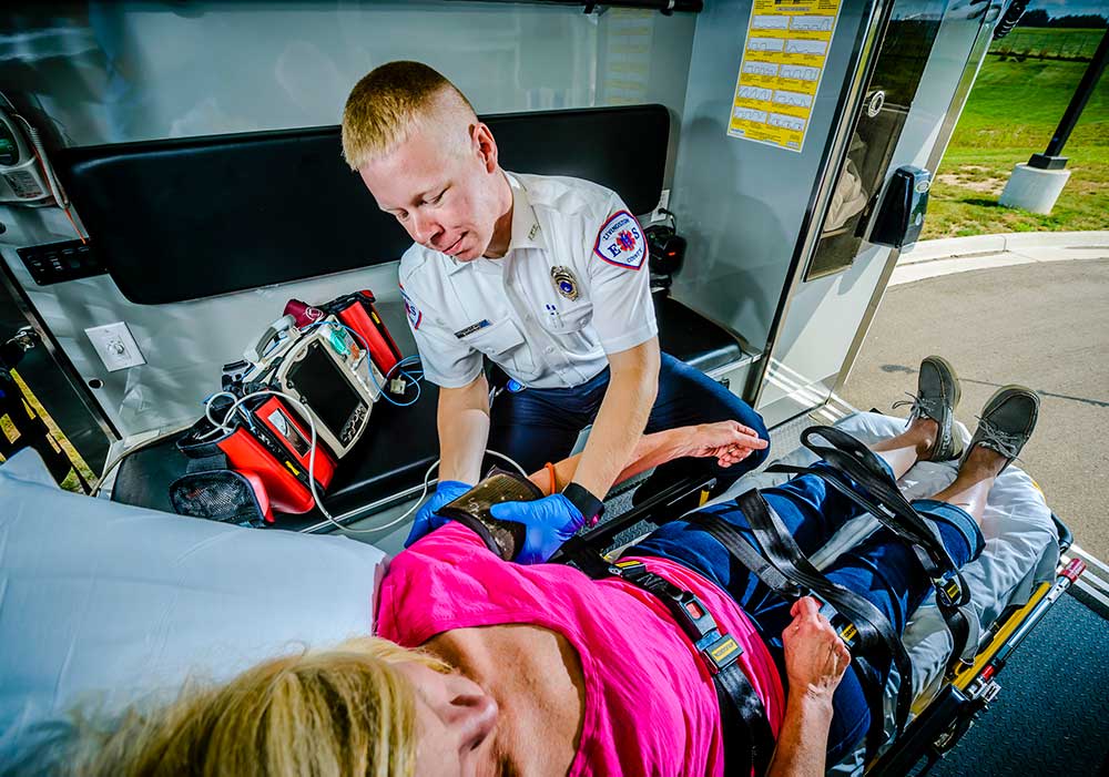 EMS Technician checking women's blood pressure inside an ambulance