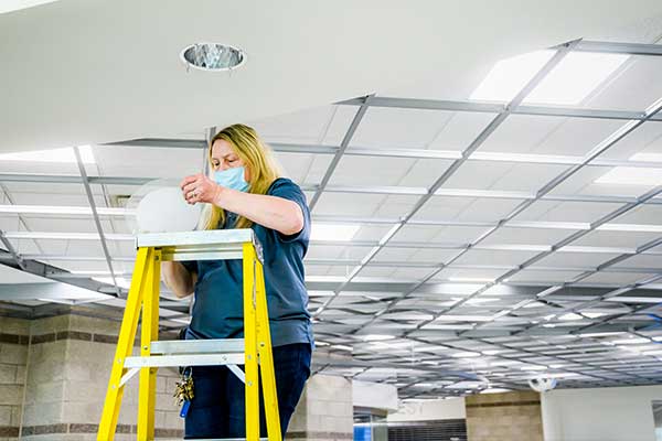 LCC employee changing a light bulb