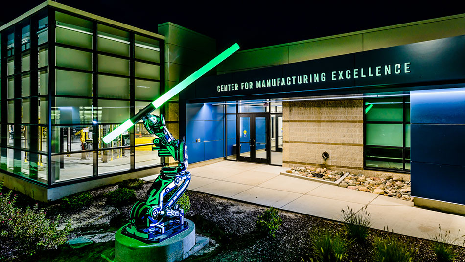 A glowing statue of a machine arm sits outside the Center for Manufacturing Excellence entrance