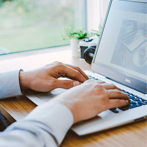 Hands typing on keyboard with code on screen.