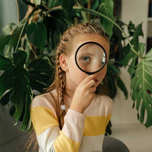 Students holding magnifying glass in front of plant