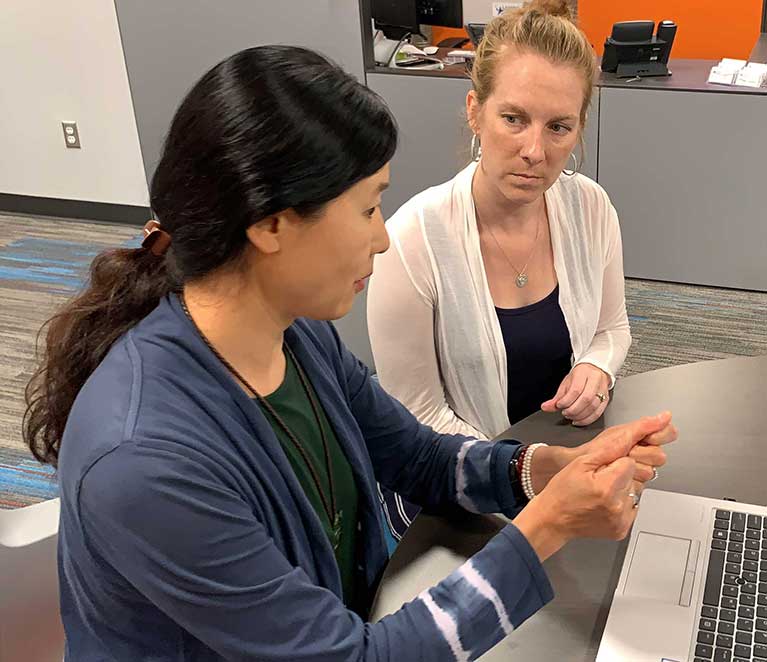 two people talking in front of a laptop