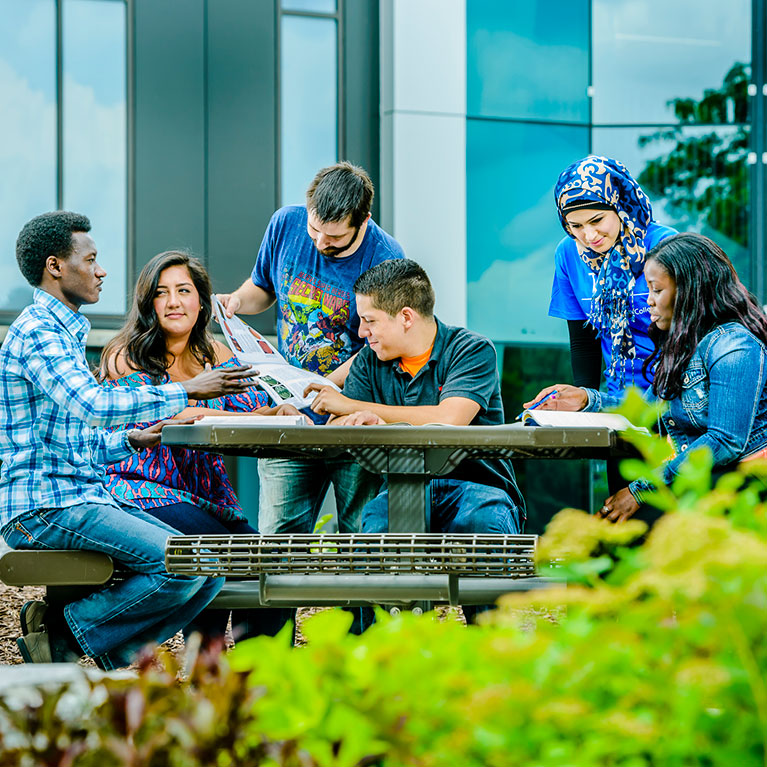 students sitting around a table outside on lcc's campus