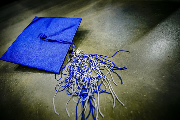 a blue LCC graduation cap on stone
