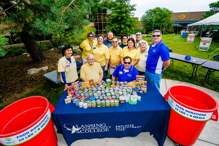 Employees in front of canned goods at employee development fund picnic