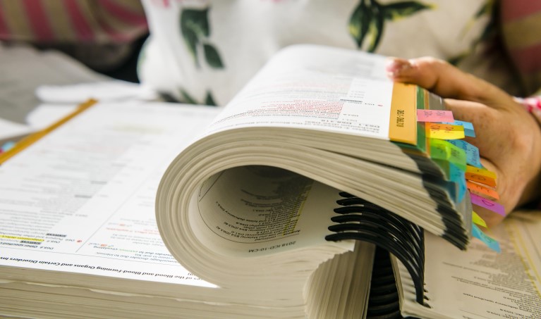 a close up image of a large textbook that is being curled by a hand 