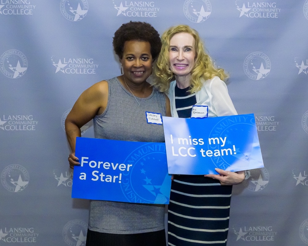 Two people are posing for a photo while holding signs that say Forever a Star and I miss my LCC team!