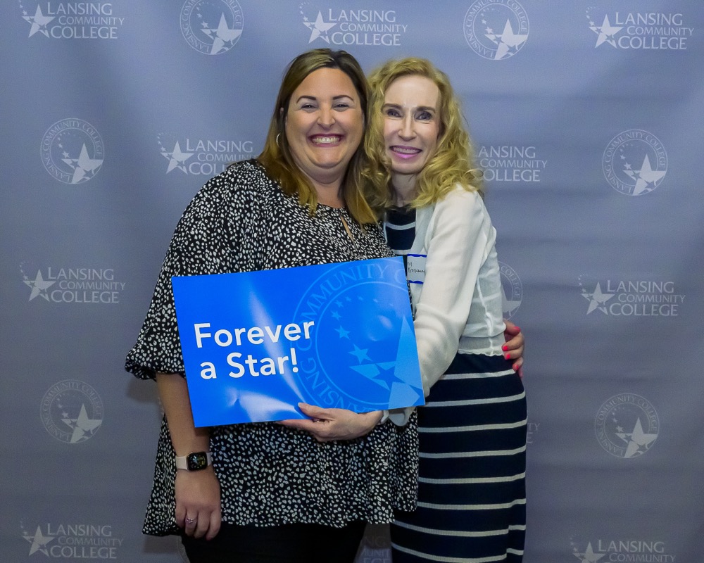 Two people posing for a photo while holding a sign that says Forever a Star.