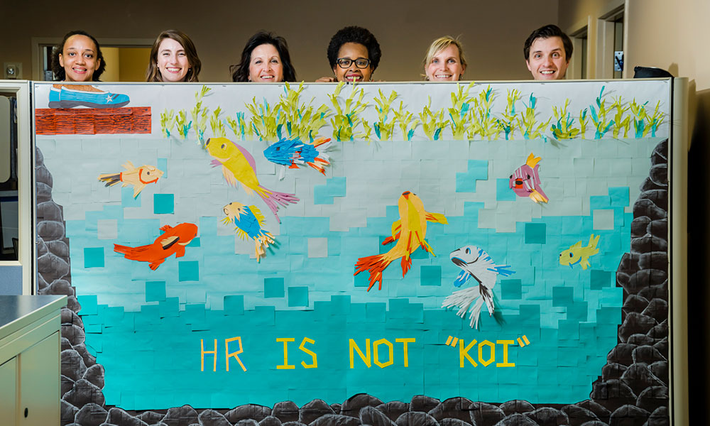 HR employees posing behind their post-it note art challenge project named - HR is not koi