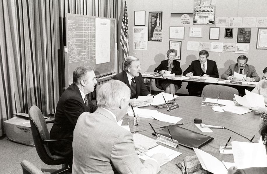 President Gannon, Trustees and Staff sit at table in the Boardroom at a Board meeting.