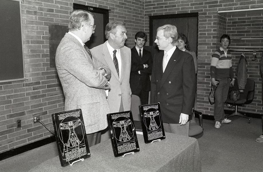 President Gannon stands with two other staff members at the front of a lecture hall.