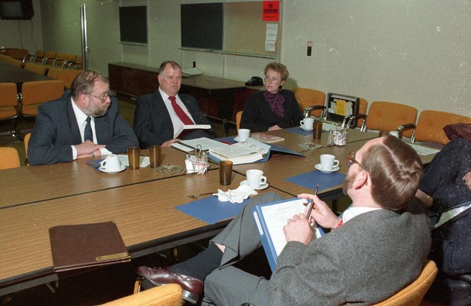 People sit around a large rectangular table during a meeting.