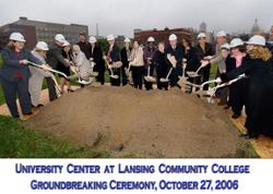 Multiple people simultaneously add a shovel-full of dirt to the pile of dirt they are standing around at the Groundbreaking Ceremony for the University Center at LCC.