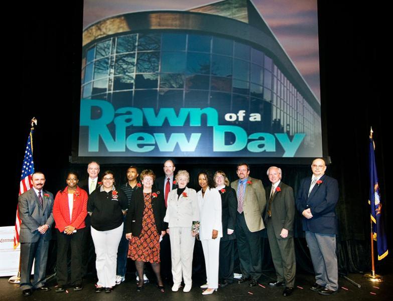 People standing together on stage at the opening event for the new health services building at the downtown campus.