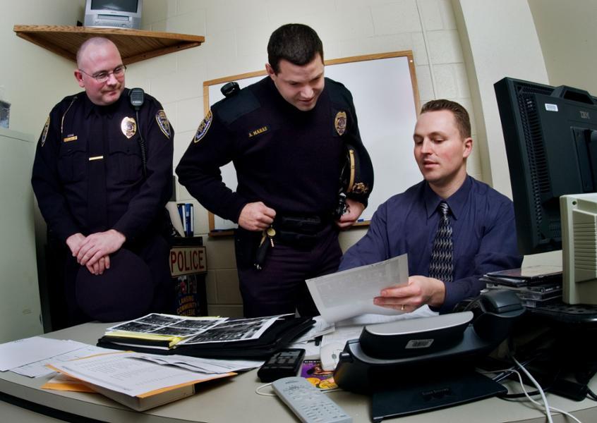 Three members of the LCC Police Department look over paperwork in the Public Safety offices.