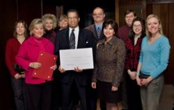 Trustee Robert Proctor stands with a group of LCC employees while holding a ceremonial check from Lansing Community College made out to the American Red Cross for tsunami relief.