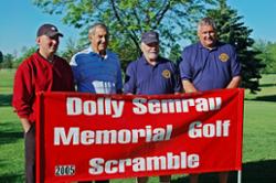 Four golfers pose by the Dolly Semrau Memorial Golf Scramble event sign.