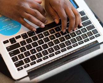 Hands typing on a computer keyboard